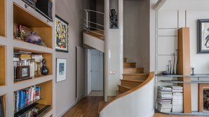 Ein modernes Interieur mit einer Wendeltreppe, Holzregalen und einem Kamin.