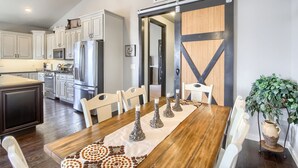 A modern kitchen with white cabinets, stainless steel appliances, and a wooden dining table with white chairs. - Perfect Lake and Mountain Views! (Monument)