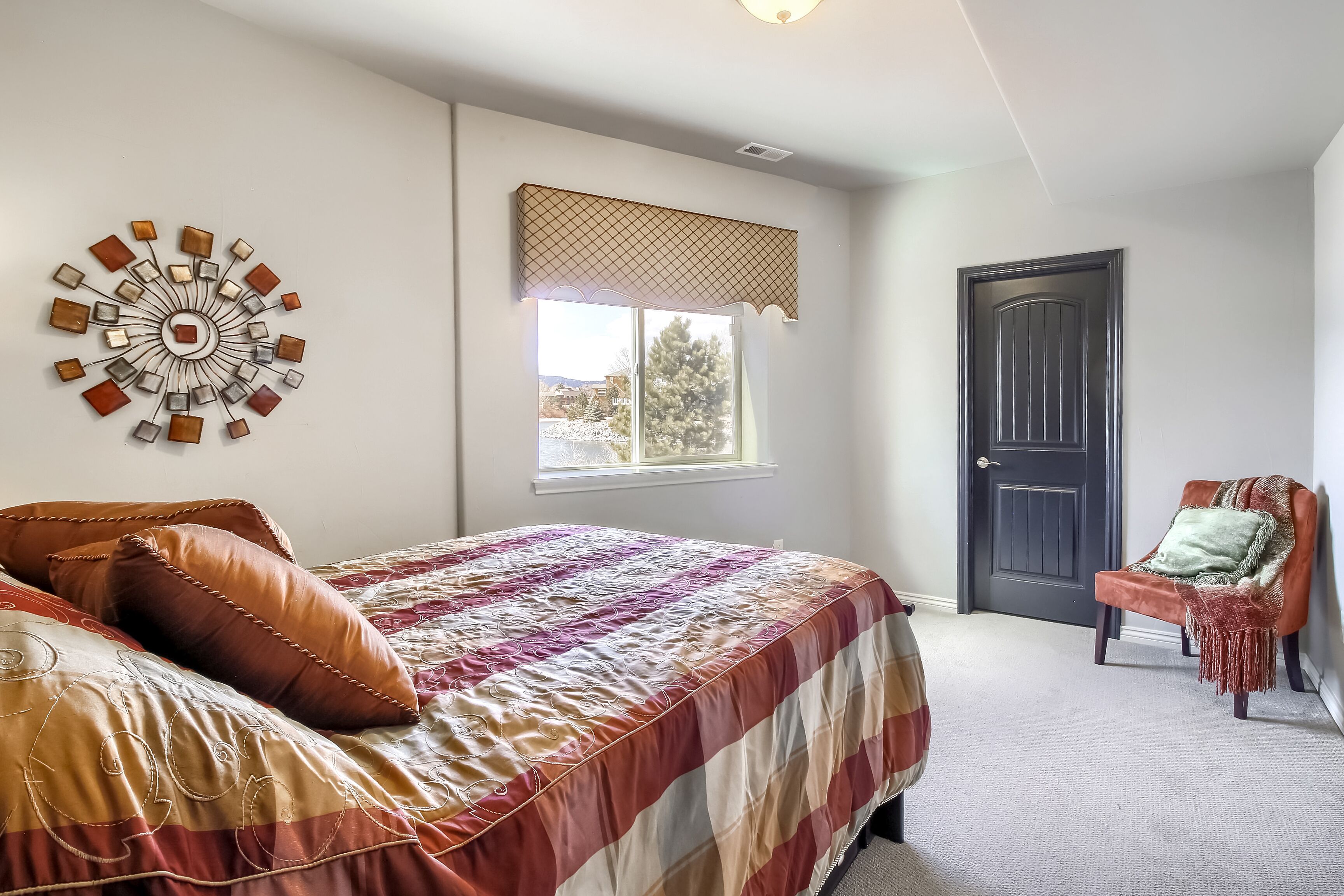 Quarto com cama, janela, porta e uma cadeira.