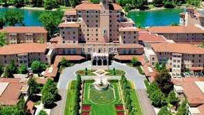 A large, multi-story building with a central courtyard, surrounded by smaller buildings and a body of water. - Perfect Lake and Mountain Views! (Monument)