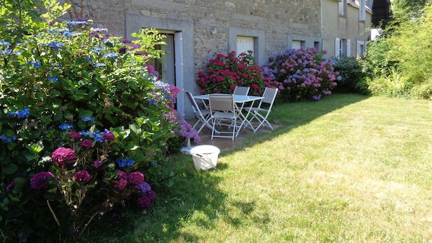 A stone building with a garden, outdoor seating, and flower beds.