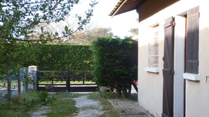 Een binnentuin met een geplaveid pad dat leidt naar een gebouw met een houten deur en luiken.