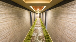 Um corredor comprido e estreito, com paredes estampadas e carpete verde.