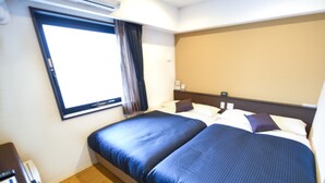 Quarto de hotel com duas camas, uma escrivaninha e uma janela com cortinas.