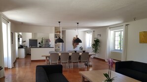 A spacious living area with a sofa, a coffee table, and a dining table with chairs. There is a kitchen in the background with a refrigerator and a sink. - House / Villa - Clermont de Beauregard (Clermont-De-Beauregard)