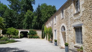 A stone building with a gravel courtyard, a covered walkway, and potted plants. - House / Villa - Clermont de Beauregard (Clermont-De-Beauregard)