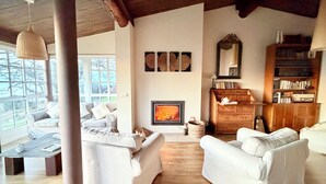 A cozy living room with two white sofas, a fireplace, and a wooden bookshelf.