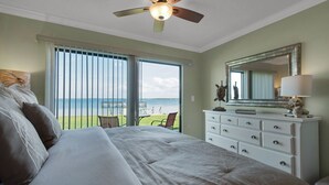 A bedroom with a large bed, a dresser, a ceiling fan, and a view of the ocean through the sliding glass door. - "Julie's Jewel"  - A Real Gem - Perfect for A Couple! (Navarre)