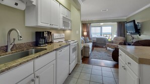 A compact kitchen with white cabinets, a granite countertop, and a coffee maker. - "Julie's Jewel"  - A Real Gem - Perfect for A Couple! (Navarre)