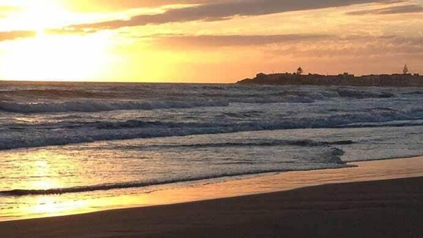 Ein Strand mit Wellen bei Sonnenuntergang.