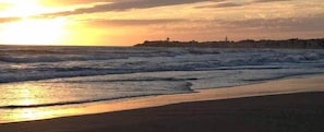 Une plage avec des vagues au coucher du soleil.