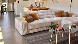 Un salon moderne avec un canapé d’angle, une table basse ronde et une lucarne.