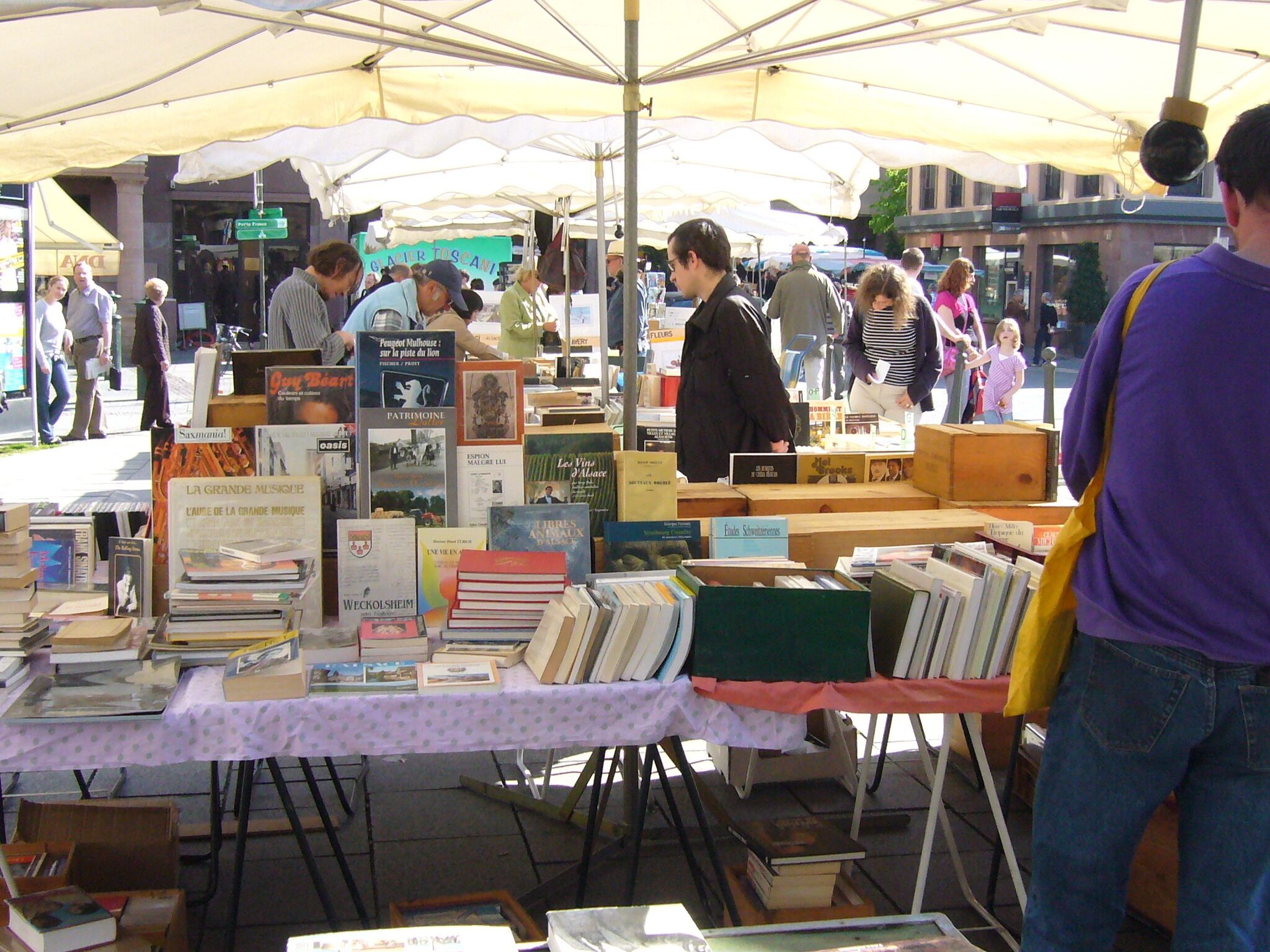A book fair with tables displaying various books under a large tent.