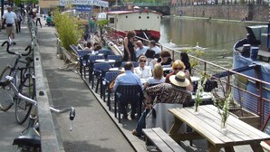 A riverside café with outdoor seating, bicycles parked along the path, and a boat docked nearby. - Apartment/ flat - Strasbourg (Strasbourg)