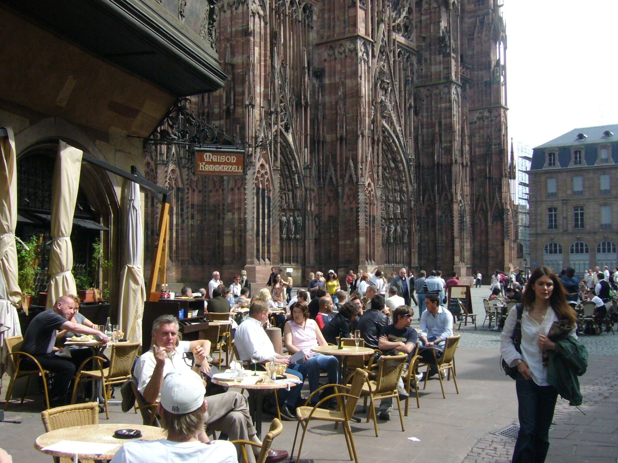 An outdoor café with tables and chairs, set against a historic building with intricate architecture.
