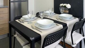 Zona pranzo con tavolo apparecchiato per quattro, forno a microonde e frigorifero.