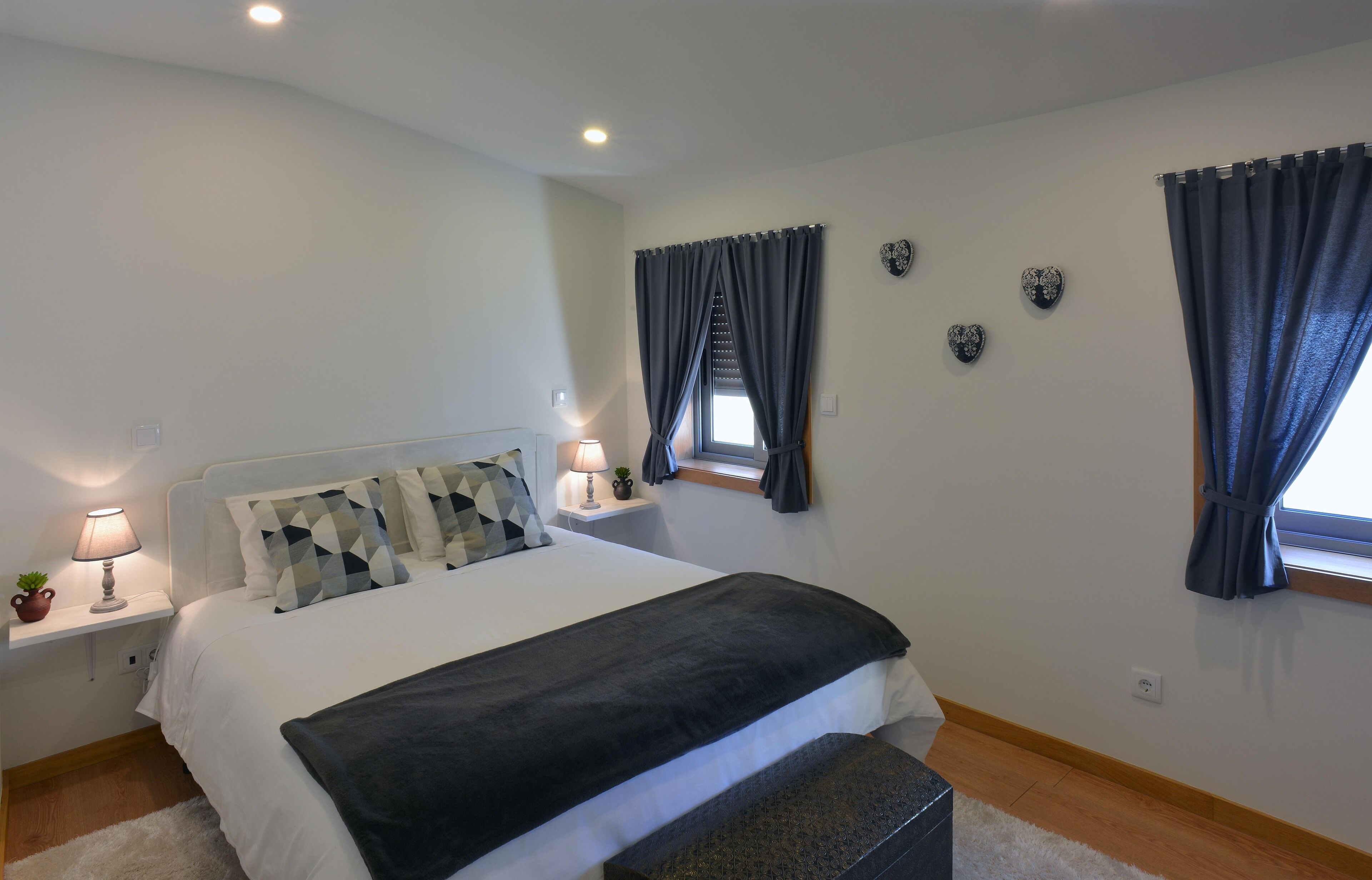 A bedroom with a bed, bedside tables, a lamp, a window with curtains, and wall decorations.