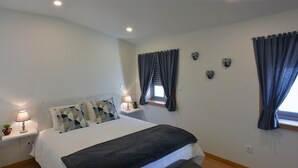 Una camera da letto con un letto, comodini, una lampada, una finestra con tende e decorazioni alle pareti.