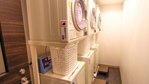 A laundry room with three stacked washing machines and a control panel. - Hotel Livemax Shinsaibashi East (Osaka)