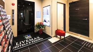 A hotel lobby with a reception desk, a digital directory, a 'Staff Only' door, and a red bench. - Hotel Livemax Shinsaibashi East (Osaka)