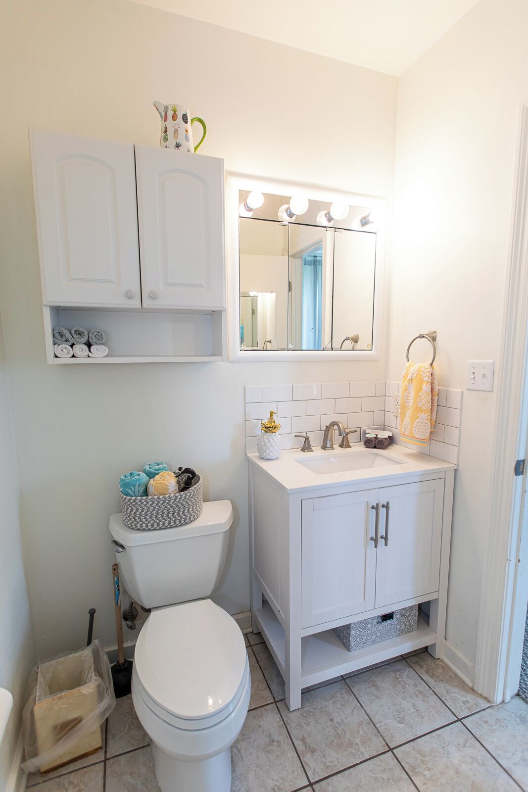 A bathroom with a white toilet, a sink with a mirror above it, and a cabinet above the sink.