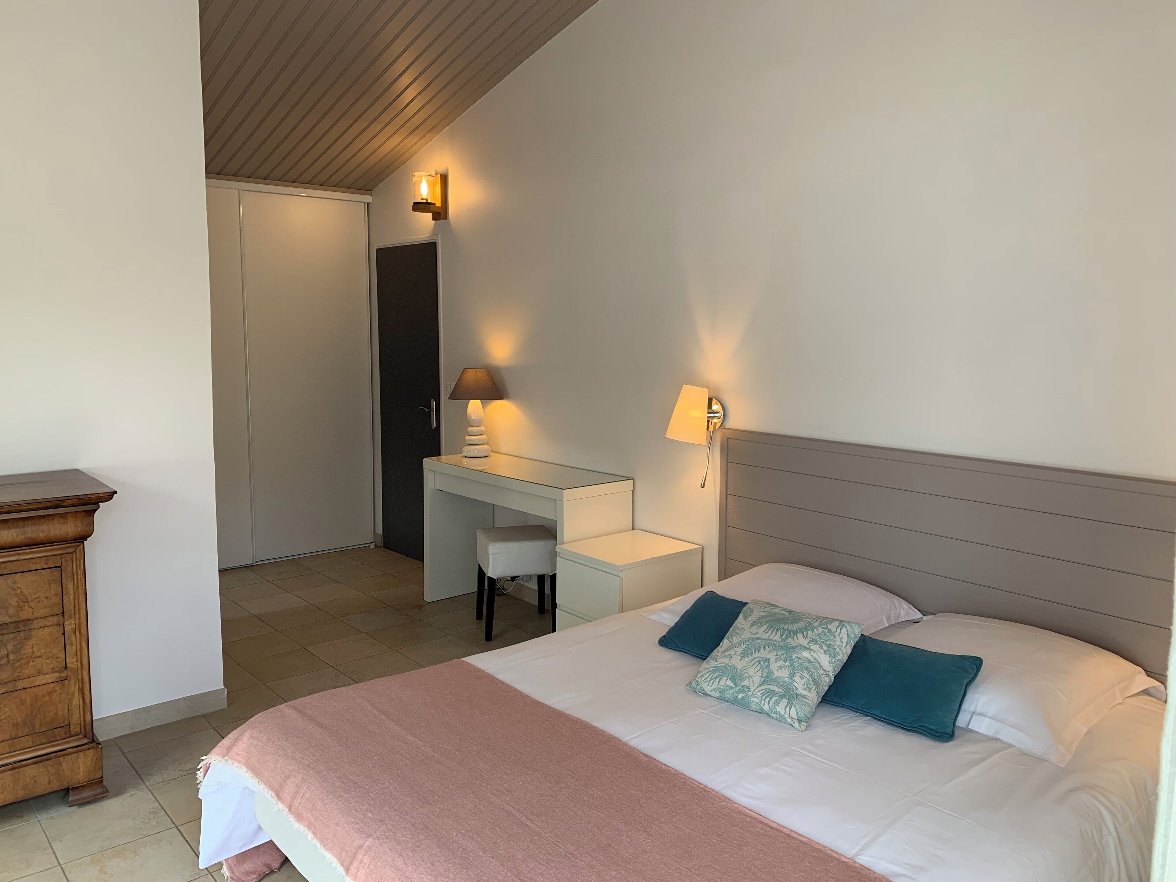 A bedroom with a bed, bedside tables, a desk, and a wardrobe.