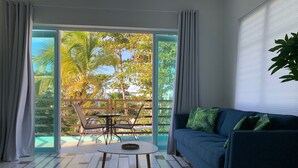 Een kamer met een bank, een klein tafeltje en uitzicht op een balkon met buitenmeubilair.