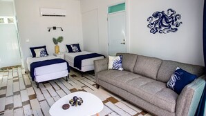 Een kamer met een bank, twee bedden, een kleine tafel en een decoratief wandobject.
