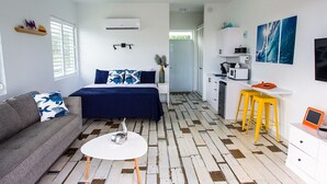 Een compacte, moderne kamer met een bed, een slaapbank en een klein eethoekje.