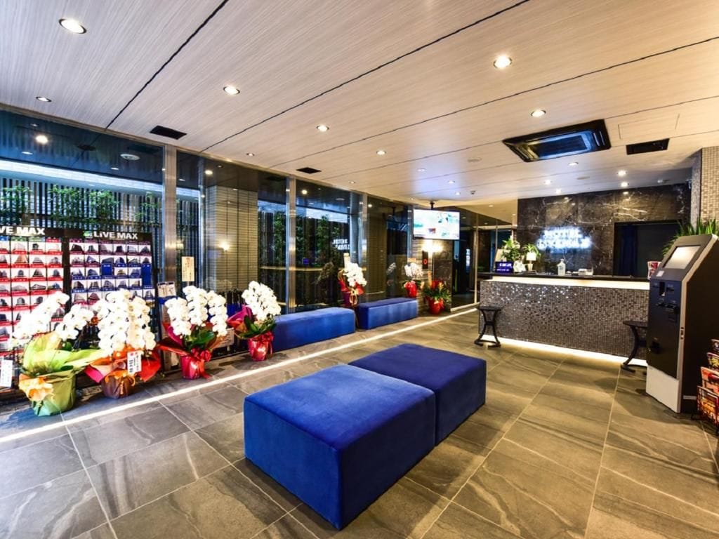 Um hall de hotel com áreas de estar, balcão de recepção e exposição de produtos.