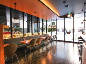 Um café moderno com piso de madeira, cadeiras de metal e iluminação pendente.