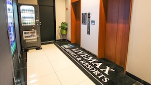 A hotel lobby with a vending machine, a potted plant, and a carpet with the hotel name. - Hotel Livemax Osaka Yodoyabashi (Osaka)