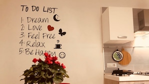 Een keuken met een notitielijst aan de muur, een potplant en een betegelde spatwand.