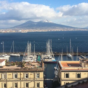 A marina with boats docked, a mountain in the background, and buildings with balconies overlooking the water. - New "Annurca" apartment with terrace (Napoli)