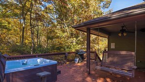 A wooden deck with a hot tub, a barbecue grill, and a swing chair. - Chimney Mountain Chalet - Spacious Pet Friendly Chalet for the Whole Family (Sautee Nacoochee)