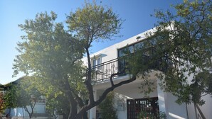 A two-story house with a balcony, surrounded by trees and a stone wall. - Apartment Srsen for 2 people in Kuciste (Kucište)