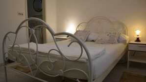A neatly made bed with a metal frame, a bedside table with a lamp, and a wall-mounted clock. - Apartment Srsen for 2 people in Kuciste (Kucište)