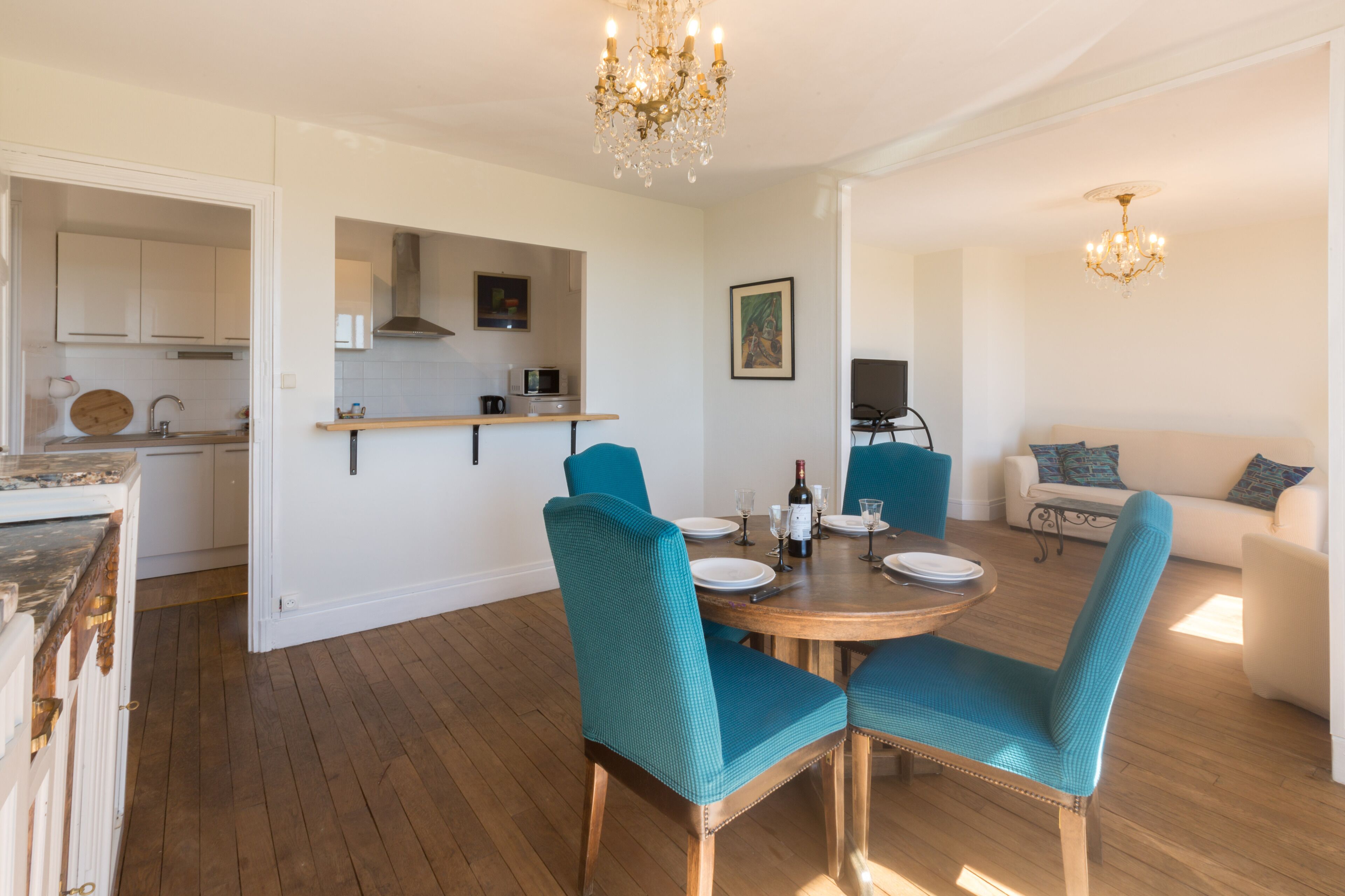 Uma sala de jantar com cadeiras azul-turquesa, uma mesa de madeira e um candelabro.
