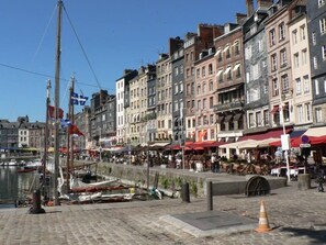 A waterfront promenade with historic buildings, outdoor seating, and a canal.