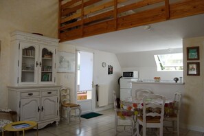 A compact kitchen with white cabinets, a microwave, and a dining area with a table and chairs.