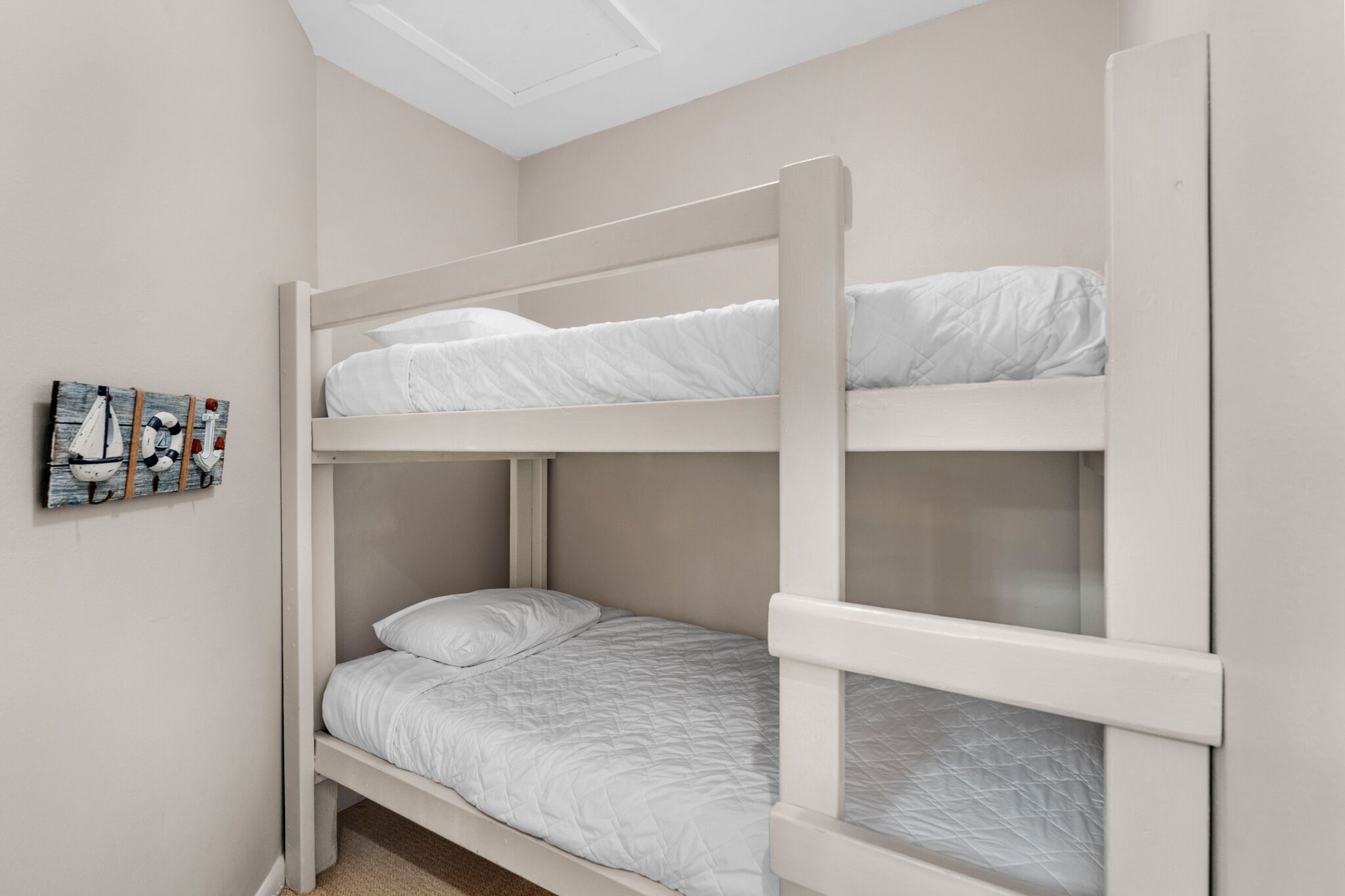 Une chambre avec un lit superposé, une lucarne, une œuvre d’art accrochée au mur et un sol recouvert de moquette.