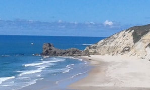 A beach with clear blue water, sandy shore, and rocky cliffs. - Family Home '' House Stone Hall '' (Pataias)