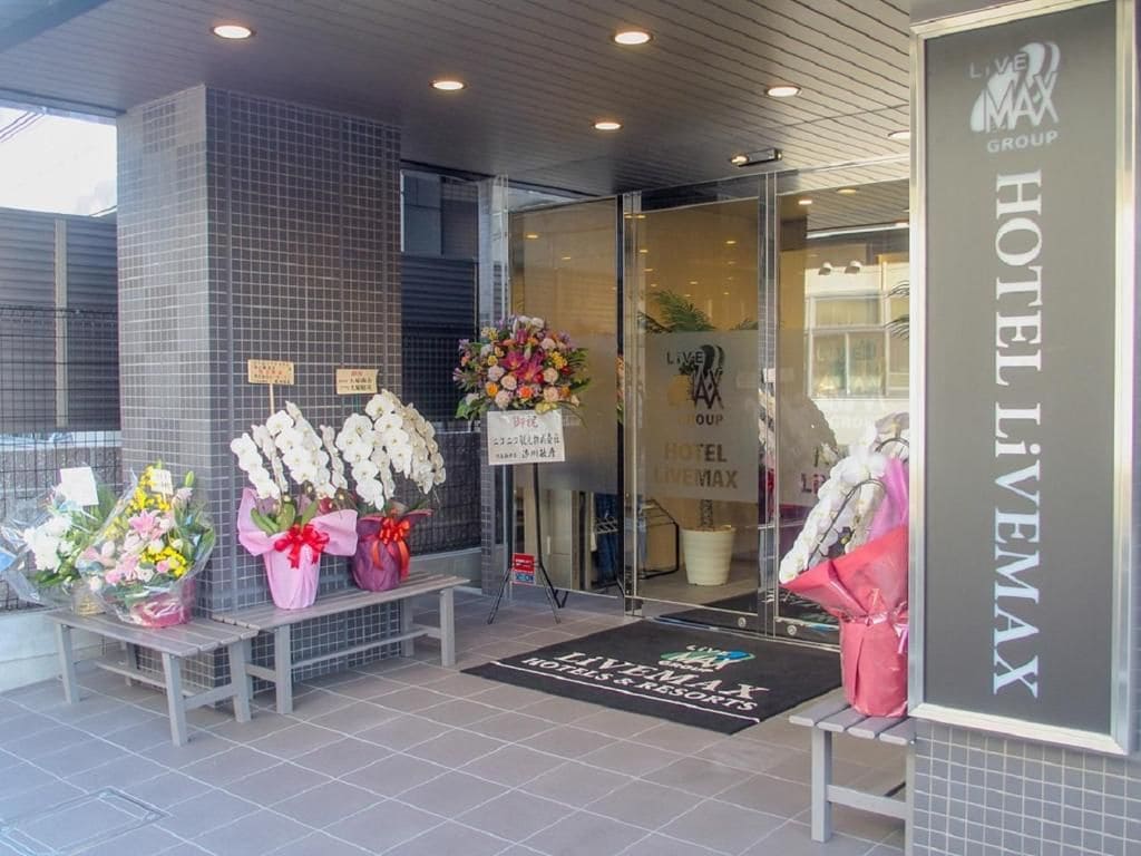 A hotel entrance with a tiled facade, a reception desk, and a welcome mat.