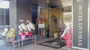 A hotel entrance with a tiled facade, a reception desk, and a welcome mat.