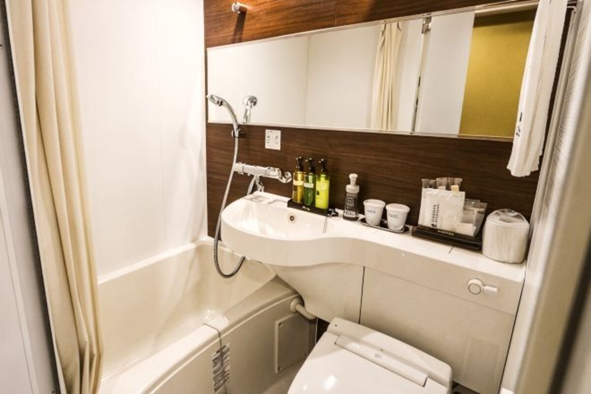 A bathroom with a sink, mirror, shower, and toilet.