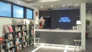 Un hall d’accueil moderne, typique des hôtels contemporains, avec un panneau numérique affichant le nom « HOTEL LIVEMAX ».