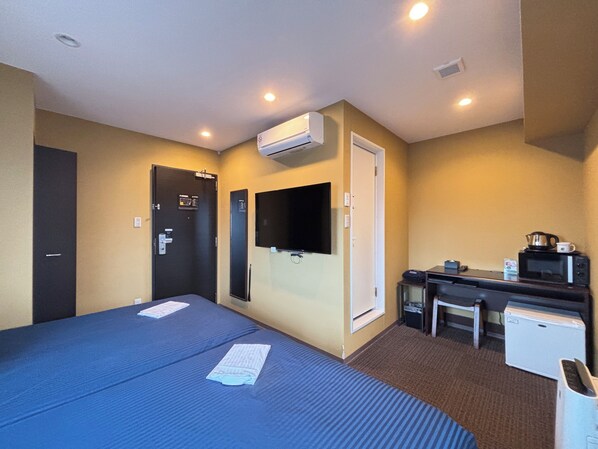 Habitación de hotel con dos camas, un escritorio, un microondas y un aire acondicionado.