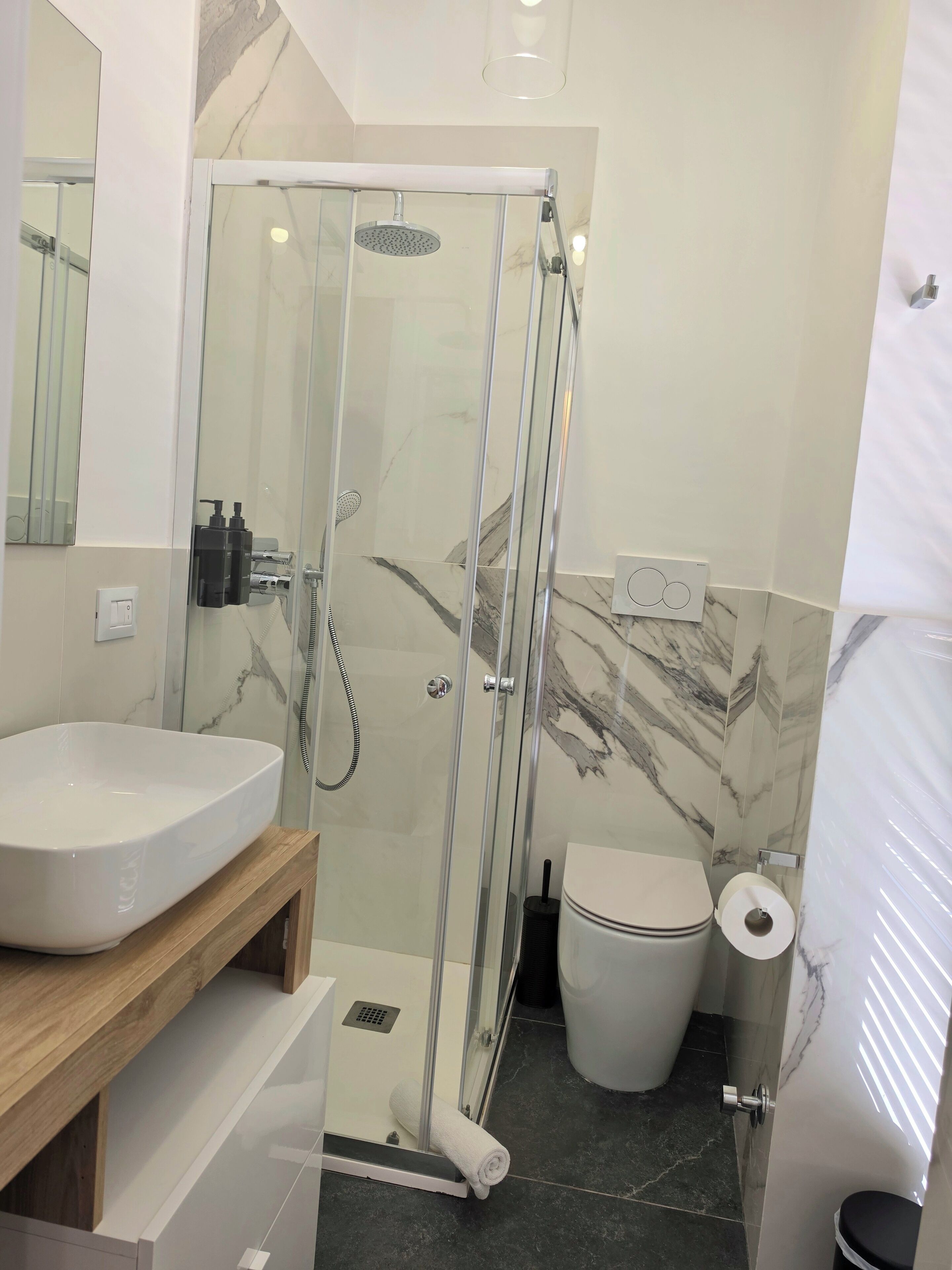 A modern bathroom with a glass-enclosed shower, a white sink, and a toilet.