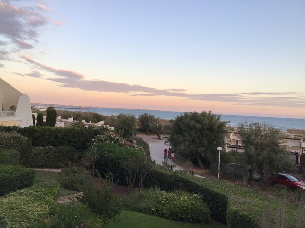 Paisaje costero con vista al mar, vegetación y algunas personas caminando.