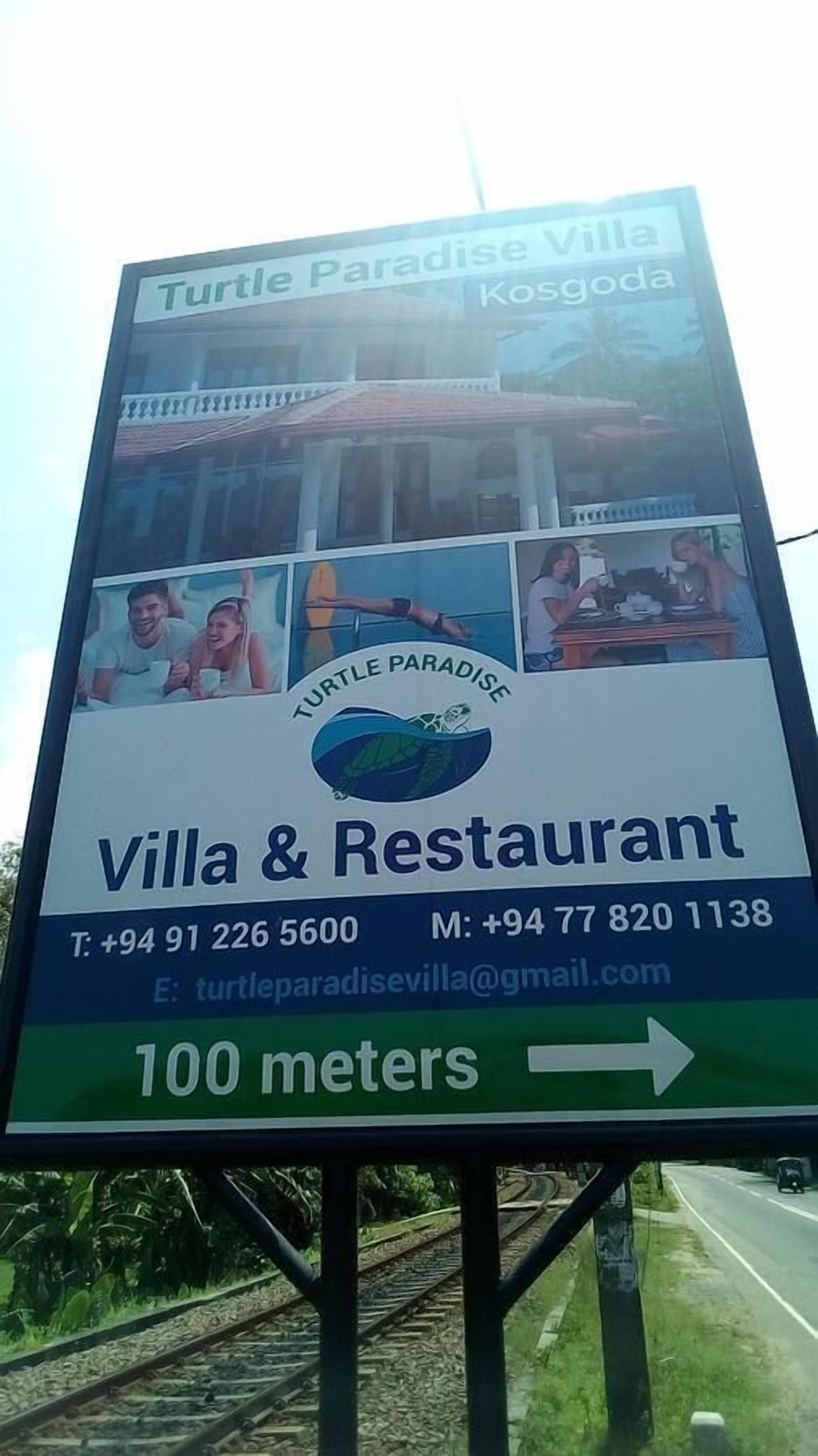 A signboard for Turtle Paradise Villa & Restaurant, including contact information and a direction arrow.